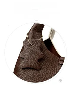 Detail of dark brown lychee grain leather bucket bag with a cute bear-shaped charm