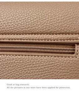 Detailansicht der genarbten Lederstruktur und des goldenen Reißverschlusses der Tasche