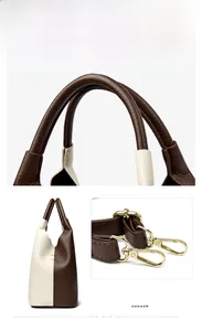 Detail of leather handbag stitching and gold-tone metal hooks on a bicolor bucket bag