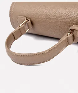 Makro-Detailansicht der beigefarbenen Handtasche aus Leder mit goldenen Metallbeschlägen