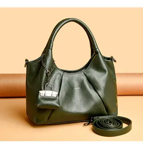 Dettaglio borsa a mano verde scuro in pelle martellata con pieghe e mini pochette