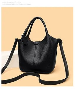 Close-up of black lychee grain leather bucket bag with dual handles and bear charm