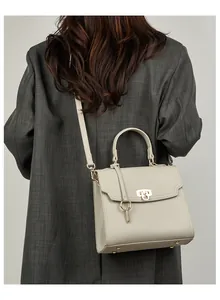 Modell mit cremefarbener Lederhandtasche mit Lychee-Muster und Goldbeschlägen