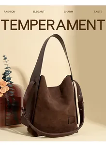 Detail view of deep brown suede tote bag with leather logo tag and wide shoulder strap