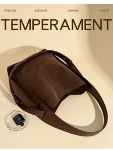 Detail view of dark brown suede bucket bag with smooth leather trim and wide strap