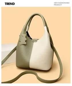 Detail of green and beige leather bucket bag with litchi texture and bear charm