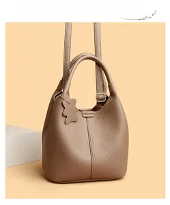 Detail of taupe lychee leather bucket bag with top handles and cute bear charm pendant