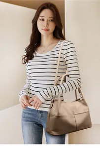 Primer plano del bolso tote beige de piel texturizada con bandolera en una modelo