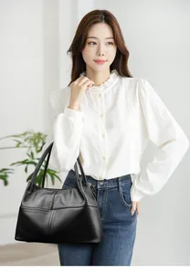 Detalle de bolso tote de cuero negro con costuras en contraste llevado por una modelo