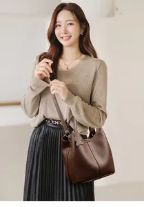 Detail of dark brown lychee grain leather bucket bag with a cute bear charm accessory