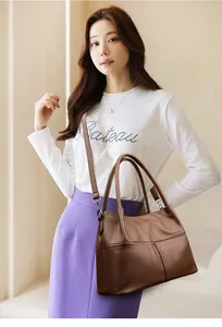 Detalle del bolso tote de cuero marrón con patrón de litchi y costuras verticales finas