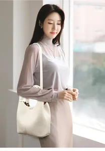 Detailed shot of cream lychee grain leather bucket bag with top handle and strap