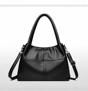 Detalle de bolso tote en cuero granulado negro con correa bandolera y costuras decorativas
