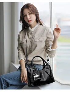 Dettaglio borsa a mezzaluna in pelle nera plissettata con manico ad anello e mini pouch
