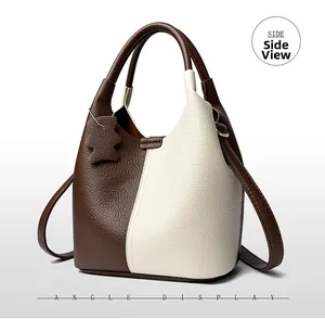 Slightly side view of two-tone leather bucket bag with bear charm and pebble texture