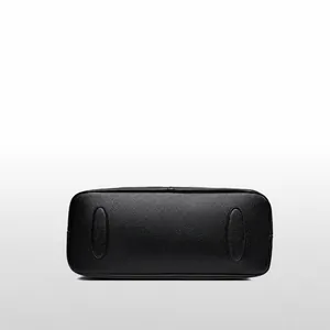 Vista detallada de la base del bolso tote de cuero negro con textura granulada y refuerzos