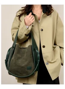 Close-up of a dark green suede bucket bag worn with a stylish khaki trench coat