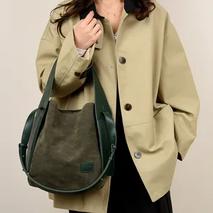 Retro dark green suede bucket bag with leather handles shown on a model