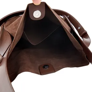 Deep brown suede bucket bag with magnetic closure and wide smooth leather shoulder strap
