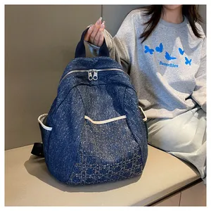 Macro view of blue denim backpack showing diamond quilted pattern and metal zippers