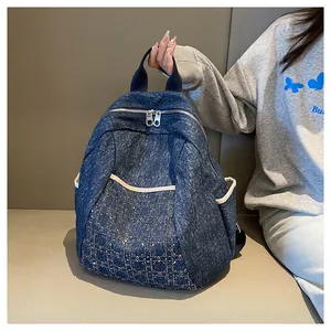 Detailed view of large navy denim backpack featuring quilted diamond pattern and studs