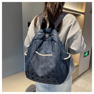 Detail of blue denim backpack showing diamond quilted pattern and side pocket on the street
