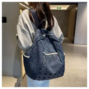 Detail of embroidered denim backpack featuring silver diamond lattice and dual zippers