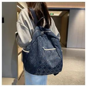 Detail of dark blue denim backpack featuring quilted diamond pattern and dual zippers