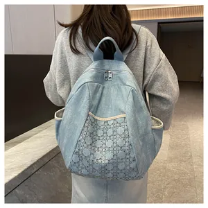 Detail of light blue denim backpack showing diamond quilted rivet patterns and silver zippers
