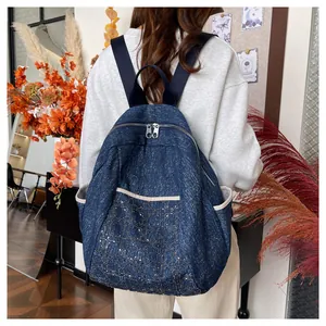 Detailed view of dark blue denim backpack featuring metallic quilted patterns on pocket