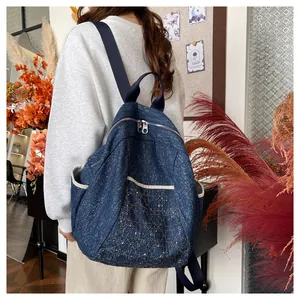 Lifestyle shot of large blue denim backpack with diamond pattern and gold embroidery