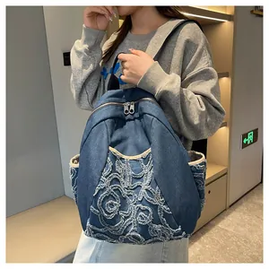 Detail shot of embroidered denim backpack with 3D floral accents on a fashion model