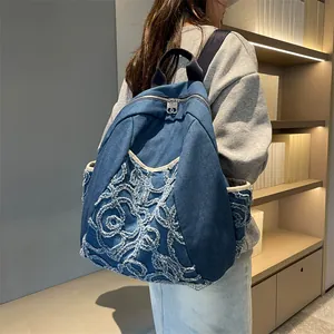 Blue denim backpack with quilted embroidery and fringe detail shown on a model