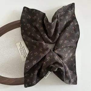 Close-up of brown floral hair scrunchie with handmade label on vintage wooden background