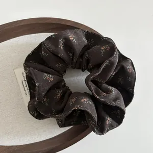 Macro detail of brown floral scrunchie showing delicate chiffon texture and vintage pattern