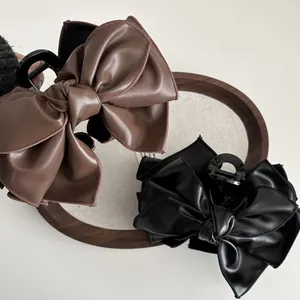 Detail von eleganten schwarzen und braunen PU-Leder Haarklammern mit edlen Nähten