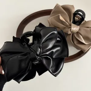 Elegante Haarklammern mit PU-Leder Schleife in Schwarz und Apricot auf einem Holztablett