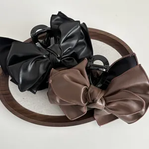 Detail von eleganten PU-Leder Schleifen-Haarklammern in Schwarz und Braun auf Holz