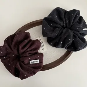 Retro polka dot wool scrunchies in burgundy and grey displayed on a wooden tray