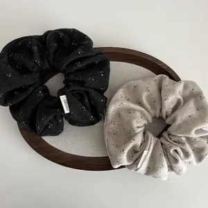 Chouchous en tricot à fleurs noir et beige sur plateau en bois pour queue de cheval