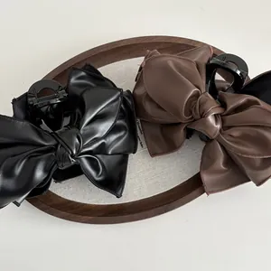 Elegante große Haarspangen aus PU-Leder mit Schleife in Schwarz und Braun auf Tablett