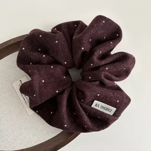 Close-up of burgundy polka dot scrunchie made of wool fabric on a wooden tray