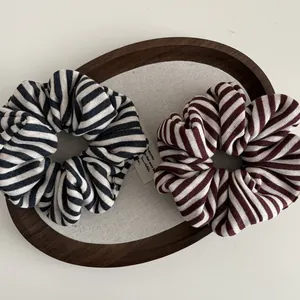 Striped knit scrunchies in black-white and red-white patterns on a wooden tray