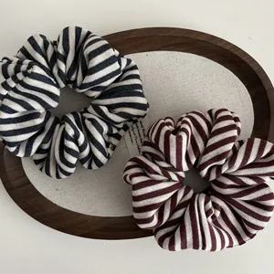 Close-up of knit striped scrunchies in navy and wine red in a wooden tray