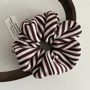 Detail of red and white striped knit scrunchie with soft pleated texture and elastic band