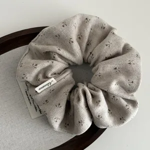 Gros plan détaillé d'un chouchou en maille beige avec de délicats motifs floraux marron