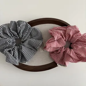Detailweergave van geblokte scrunchies in zwart-wit en rood-wit op een presentatieblad
