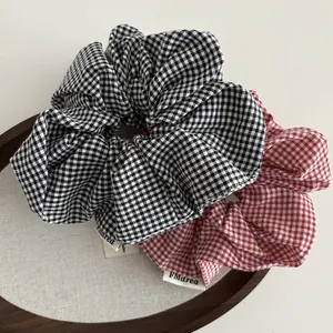 Klassieke geruite scrunchie set in rood en zwart op een ronde houten presentatieplaat