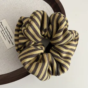 Close-up of striped knit scrunchie with soft mustard yellow and grey ribbed texture
