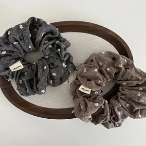 Brown and grey cotton-linen scrunchies with 3D colorful dots on a wooden tray